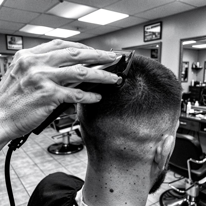 Barber's hands guiding clippers along a skin fade