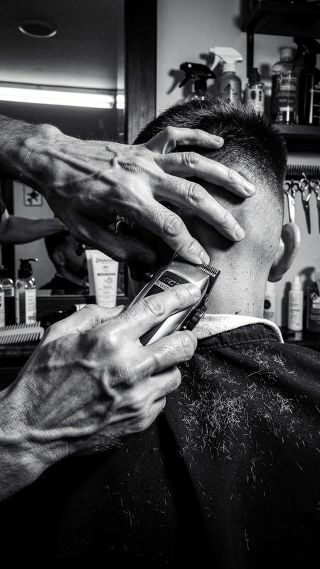 Barber detailing a fresh skin fade with clippers