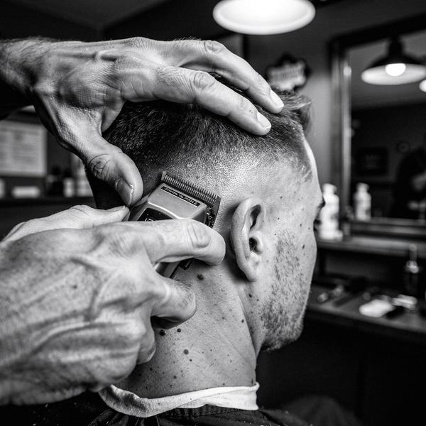 Barber working clippers along a client's clean neckline mid skin fade